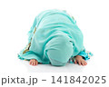 Charming young Asian Muslim child in traditional headscarf bowing down in prayer during holy month Ramadan. 141842025