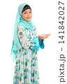 Half length portrait of cute young Asian Muslim girl praying with open hands looking at camera isolated on white background. 141842027