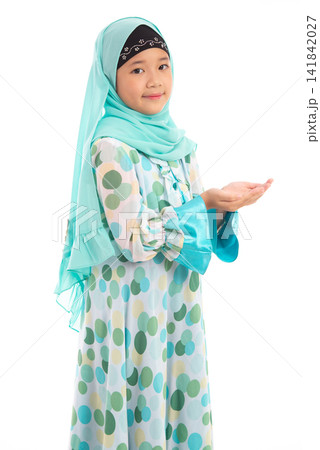 Half length portrait of cute young Asian Muslim girl praying with open hands looking at camera isolated on white background. 141842027