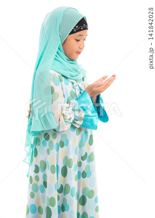 Side view portrait of cute young Asian Muslim girl praying with open hands isolated on white background. Side view portrait of cute young Asian Muslim girl praying with open hands isolated on white background. 141842028