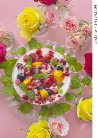 ピンクの背景に映えるベリーとフルーツのケーキと色鮮やかなバラの花々 ピンクの背景に映えるベリーとフルーツのケーキと色鮮やかなバラの花々 141842304