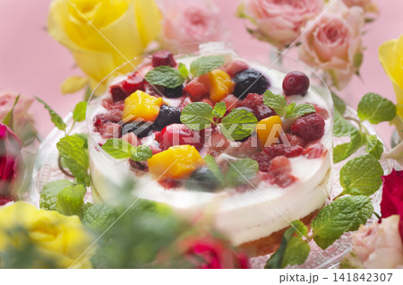 ピンクの背景に映えるベリーとフルーツのケーキと色鮮やかなバラの花々 141842307