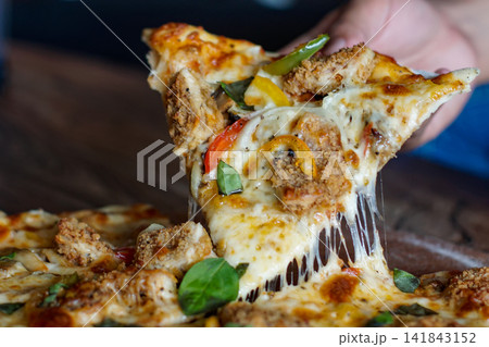 Hand Holding Crispy Chicken Pizza Slice with Melting Cheese 141843152