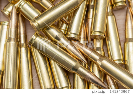 Closeup pile of brass rifle cartridges with pointed copper bullets 141843967