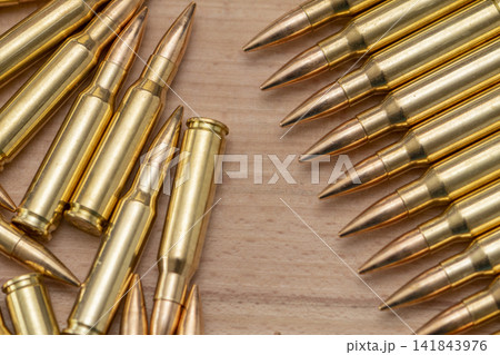 Rifle cartridges arranged in rows and scattered on wooden surface 141843976