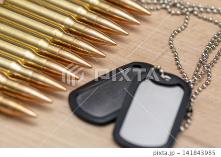 Closeup of rifle cartridges and blank military dog tags on wood 141843985