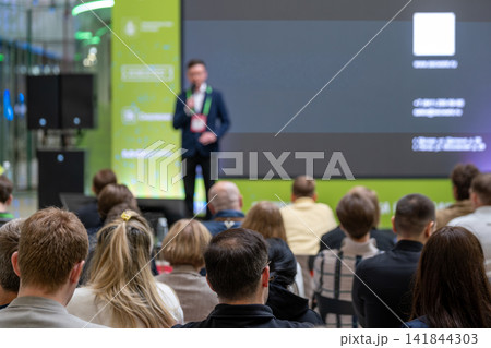 Presenter speaks beside dark digital slide at conference 141844303