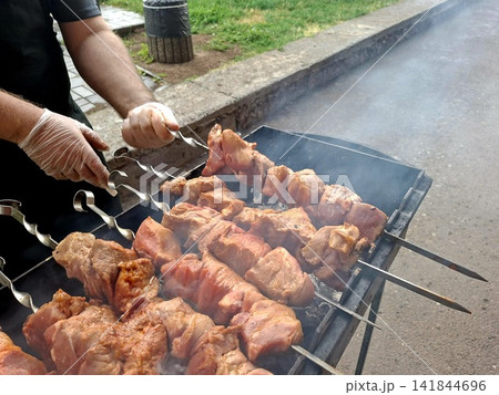 Close up of savory marinate pork meat skewers roasting over smoky charcoal coals on outdoor barbecue grill during summer picnic cooking Close up of savory marinate pork meat skewers roasting over smoky charcoal coals on outdoor barbecue grill during summer picnic cooking 141844696
