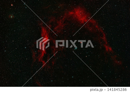 Red arching emission nebula Sharpless 2-129 surrounded by a dense field of distant stars in deep space. Red arching emission nebula Sharpless 2-129 surrounded by a dense field of distant stars in deep space. 141845286