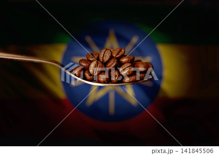A spoon filled with roasted coffee beans on the background of the flag of Ethiopia. Concept: export and import of Ethiopian coffee beans, delivery of goods. 141845506