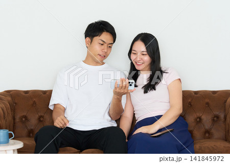 スマートフォンを操作する若い男女 スマートフォンを操作する若い男女 141845972