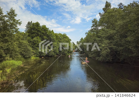 Eco tourism concept: tourists paddleboarding on Oredezh river exploring pure wild nature and pristine green forests of Siversky, Russia. Eco tourism concept: tourists paddleboarding on Oredezh river exploring pure wild nature and pristine green forests of Siversky, Russia. 141846624