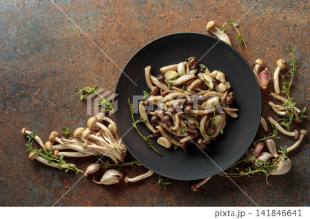 Fried shimeji mushrooms with thyme and garlic on a black plate. Fried shimeji mushrooms with thyme and garlic on a black plate. 141846641