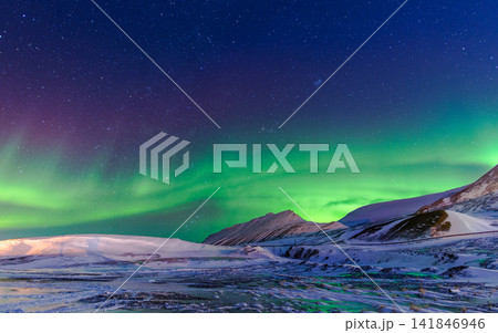 Aurora Borealis Over Snowy Arctic Mountains and Starry Night Sky Aurora Borealis Over Snowy Arctic Mountains and Starry Night Sky 141846946