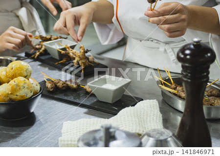 Chefs preparing creative cuisine, seasoning flavorful skewers and healthy appetizers, focusing on gastronomy, sustainability, and global culinary artistry for International Chefs Day Chefs preparing creative cuisine, seasoning flavorful skewers and healthy appetizers, focusing on gastronomy, sustainability, and global culinary artistry for International Chefs Day 141846971