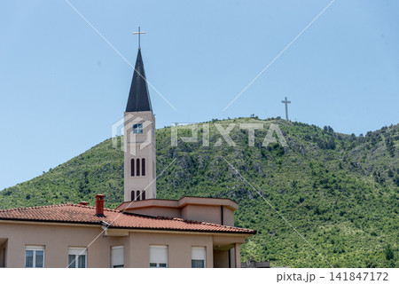 Catholic church temple in city Mostar in Bosnia and Herzegovina, mountain view Catholic church temple in city Mostar in Bosnia and Herzegovina, mountain view 141847172