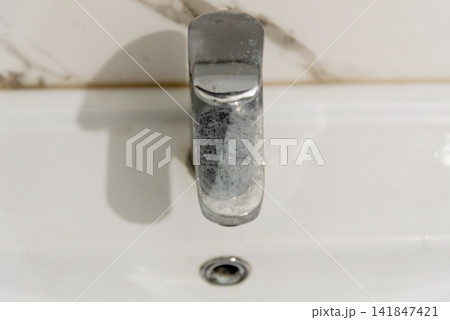 Dirty chrome tap faucet in bathroom covered plaque limescale due to hard water Dirty chrome tap faucet in bathroom covered plaque limescale due to hard water 141847421