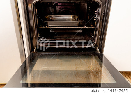 Oven with open dirty door smeared old dried grease, kitchen appliances equipment Oven with open dirty door smeared old dried grease, kitchen appliances equipment 141847485