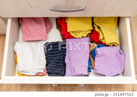 Open drawer shelf of wardrobe, keeping storage by stacks of children clothes Open drawer shelf of wardrobe, keeping storage by stacks of children clothes 141847523