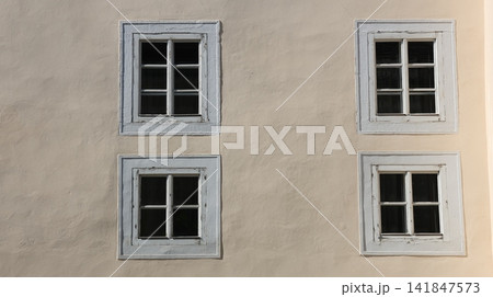 four symmetrical white-framed windows on a cream plaster wall, four symmetrical white-framed windows on a cream plaster wall, 141847573