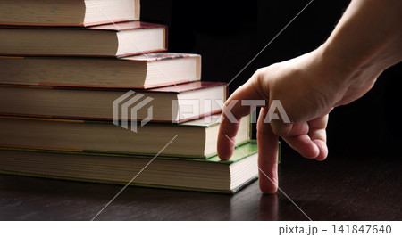Hand walking on a ladder made of books 141847640