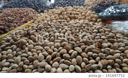 Large pile of almonds in shell kept for sale at a dry fruit shop in a busy local market, healthy food sales concept Large pile of almonds in shell kept for sale at a dry fruit shop in a busy local market, healthy food sales concept 141847752