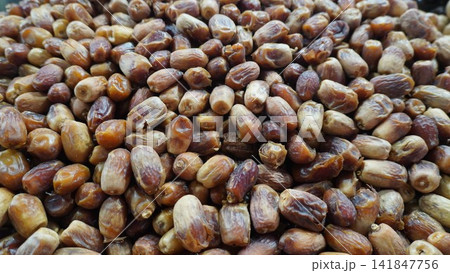 Large pile of fresh brown dates on display at a local market stall, healthy food snack commerce and retail concept Large pile of fresh brown dates on display at a local market stall, healthy food snack commerce and retail concept 141847756