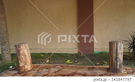 Rustic wooden log benches placed against a minimalist beige and brown wall in an outdoor garden setting, outdoor concept Rustic wooden log benches placed against a minimalist beige and brown wall in an outdoor garden setting, outdoor concept 141847797