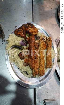 Vertical high angle shot of a steel platter containing South Asian seekh kababs and chicken tikka on rice, food concept Vertical high angle shot of a steel platter containing South Asian seekh kababs and chicken tikka on rice, food concept 141848127