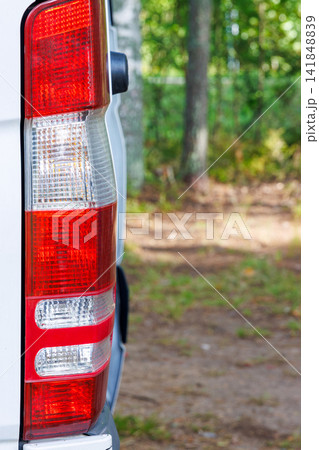 Vertical close-up of the rear taillight of a white campervan parked at a woodland campsite in Finland. Vertical close-up of the rear taillight of a white campervan parked at a woodland campsite in Finland. 141848839