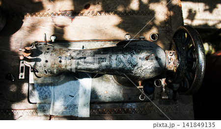 Kharkiv, Ukraine - July 15, 2021: Top view of weathered Singer sewing machine on wooden table Kharkiv, Ukraine - July 15, 2021: Top view of weathered Singer sewing machine on wooden table 141849135