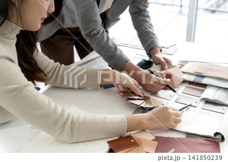 Asian adult women designers collaborate selecting material swatches color palettes for interior project planning bright modern office studio workspace 141850239