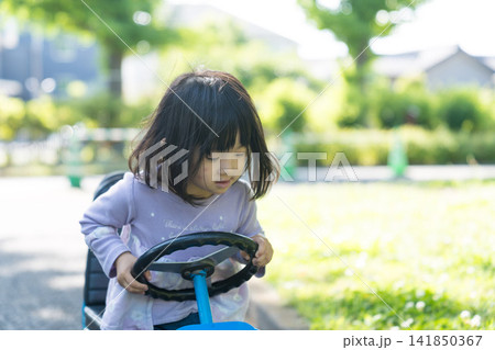 公園の青いゴーカートを笑顔で運転する日本人の女の子の幼児 公園の青いゴーカートを笑顔で運転する日本人の女の子の幼児 141850367