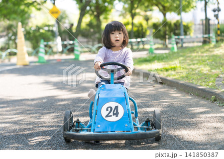 公園の青いゴーカートを笑顔で運転する日本人の女の子の幼児 公園の青いゴーカートを笑顔で運転する日本人の女の子の幼児 141850387