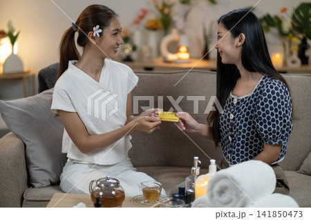 Asian women exchanging credit card payment during spa treatment relaxation wellness service at home comfortable environment Asian women exchanging credit card payment during spa treatment relaxation wellness service at home comfortable environment 141850473