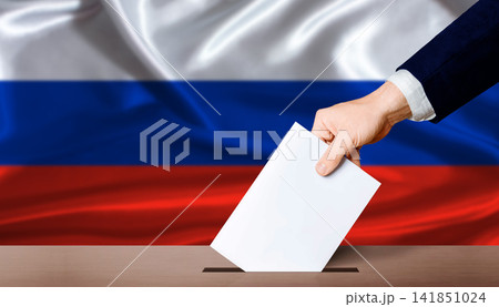 Russia Parliamentary vote 2026. Hand placing a ballot in ballot box with the Russian flag in the background Russia Parliamentary vote 2026. Hand placing a ballot in ballot box with the Russian flag in the background 141851024