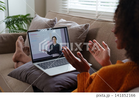 African American female student listens to an online lesson using a laptop, watches a webinar, studies remotely, the teacher and other students are on the laptop screen. E-learning 141852166