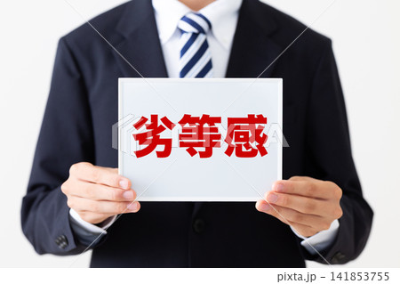 劣等感のホワイトボードを持つリクルートスーツを着た若い男性ビジネスマン 劣等感のホワイトボードを持つリクルートスーツを着た若い男性ビジネスマン 141853755