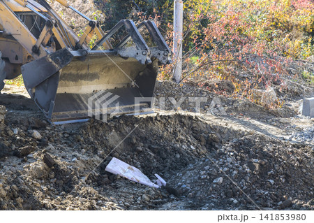 Construction equipment digs trench in rural area Construction equipment digs trench in rural area 141853980