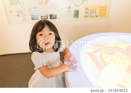 博物館の光るインタラクティブ展示台に手を触れる日本人の女の子の幼児 141854025