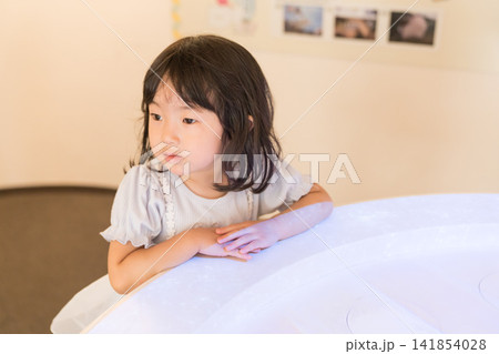 博物館の光るインタラクティブ展示台に手を触れる日本人の女の子の幼児 141854028