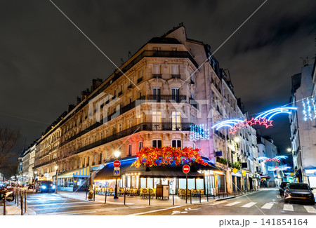 Traditional Parisian corner cafe decorated with Christmas lights at night in Paris 141854164
