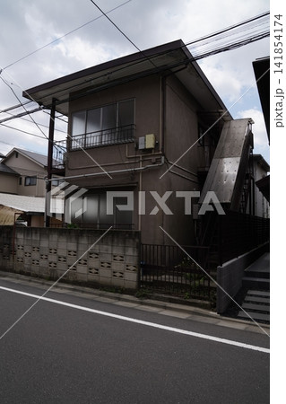 昭和の面影を残す古い集合住宅の外観と、電線が交差する穏やかな生活道路のストリートビュー 昭和の面影を残す古い集合住宅の外観と、電線が交差する穏やかな生活道路のストリートビュー 141854174