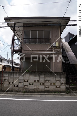 昭和の面影を残す古い集合住宅の外観と、電線が交差する穏やかな生活道路のストリートビュー 昭和の面影を残す古い集合住宅の外観と、電線が交差する穏やかな生活道路のストリートビュー 141854175