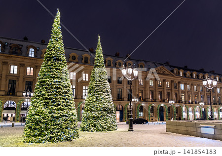 Illuminated Christmas trees on snowy Place Vendome at night in Paris 141854183