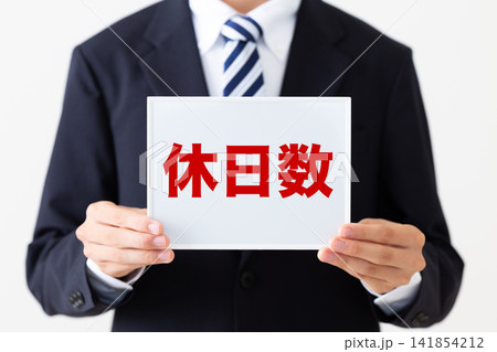 休日数のホワイトボードを持つリクルートスーツを着た若い男性ビジネスマン 141854212