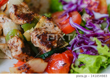 Grilled Meat Close Up with Fresh Vegetables and Colorful Salad 141854983