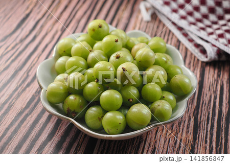 Amla fruits are gathered in a bowl on a wooden surface Amla fruits are gathered in a bowl on a wooden surface 141856847