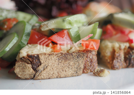 Fresh vegetables on bread placed on a white plate Fresh vegetables on bread placed on a white plate 141856864