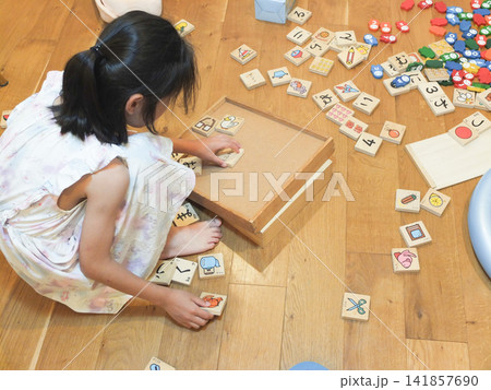おもちゃが散らかった部屋にいるワンピース姿の少女 おもちゃが散らかった部屋にいるワンピース姿の少女 141857690